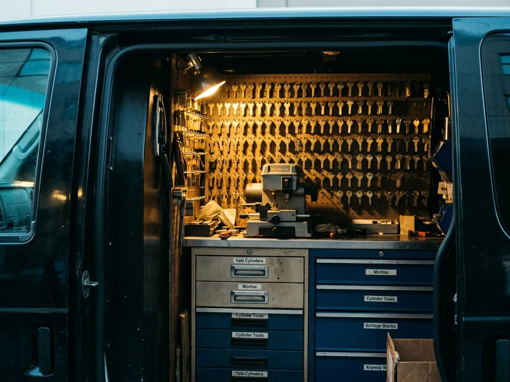 Open side door of the service van showing the pegboard of brass key blanks, key cutting machine and labelled tool drawers