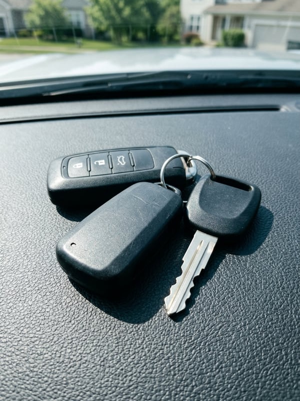 Two programmed smart key fobs and a freshly cut key resting on a car dashboard